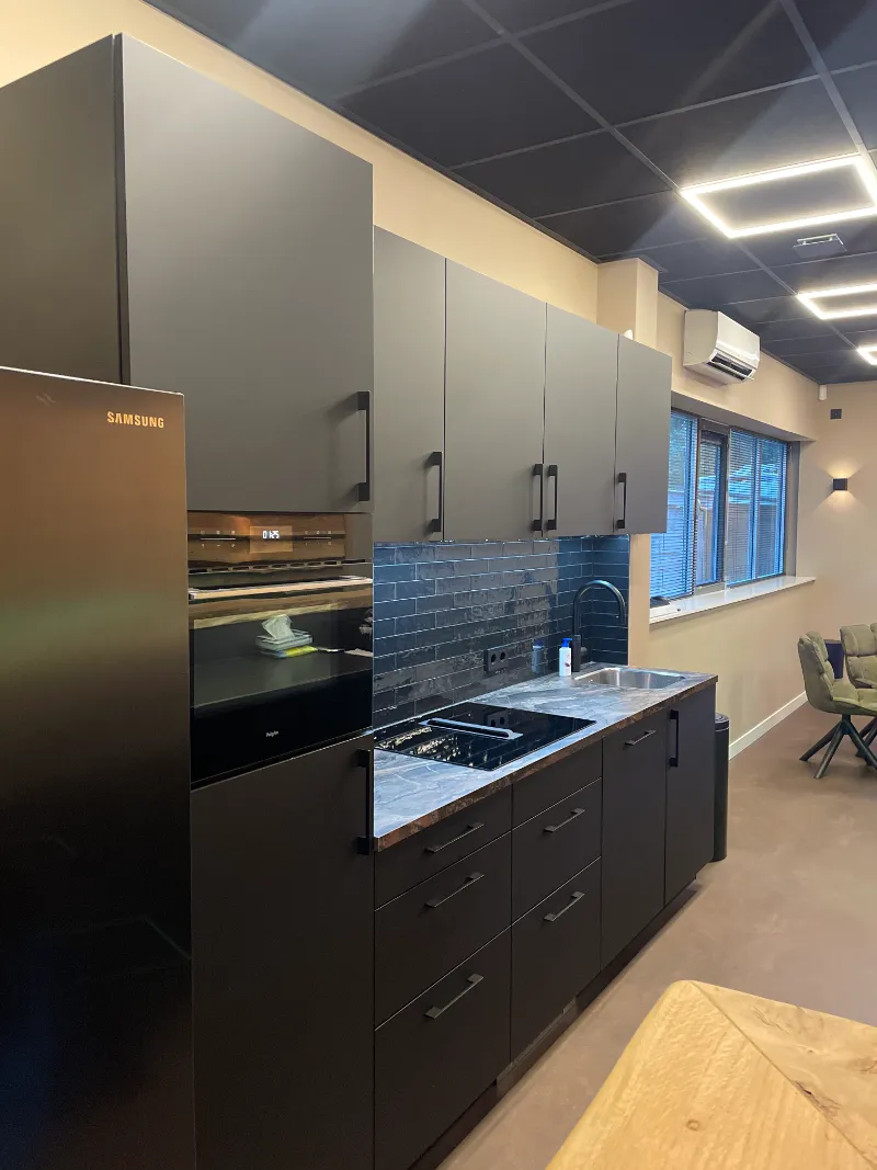 Een keuken met zwarte kasten en een fornuis.