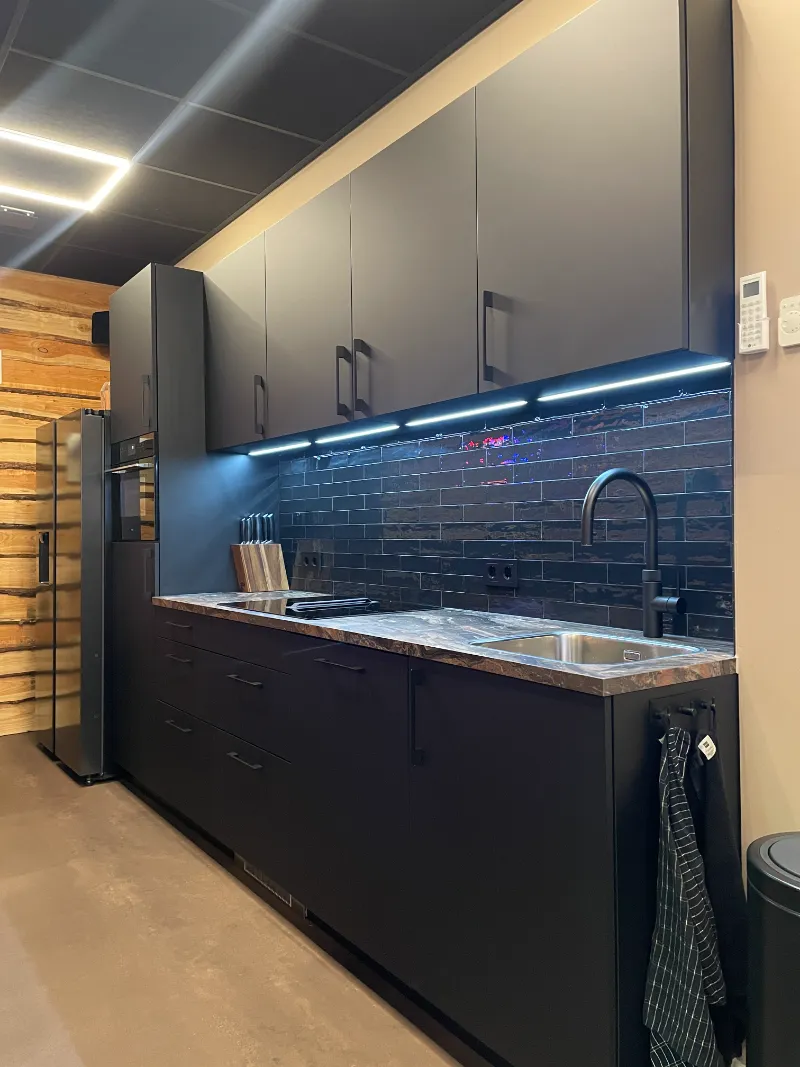 Een zwarte keuken met kasten en een spoelbak.