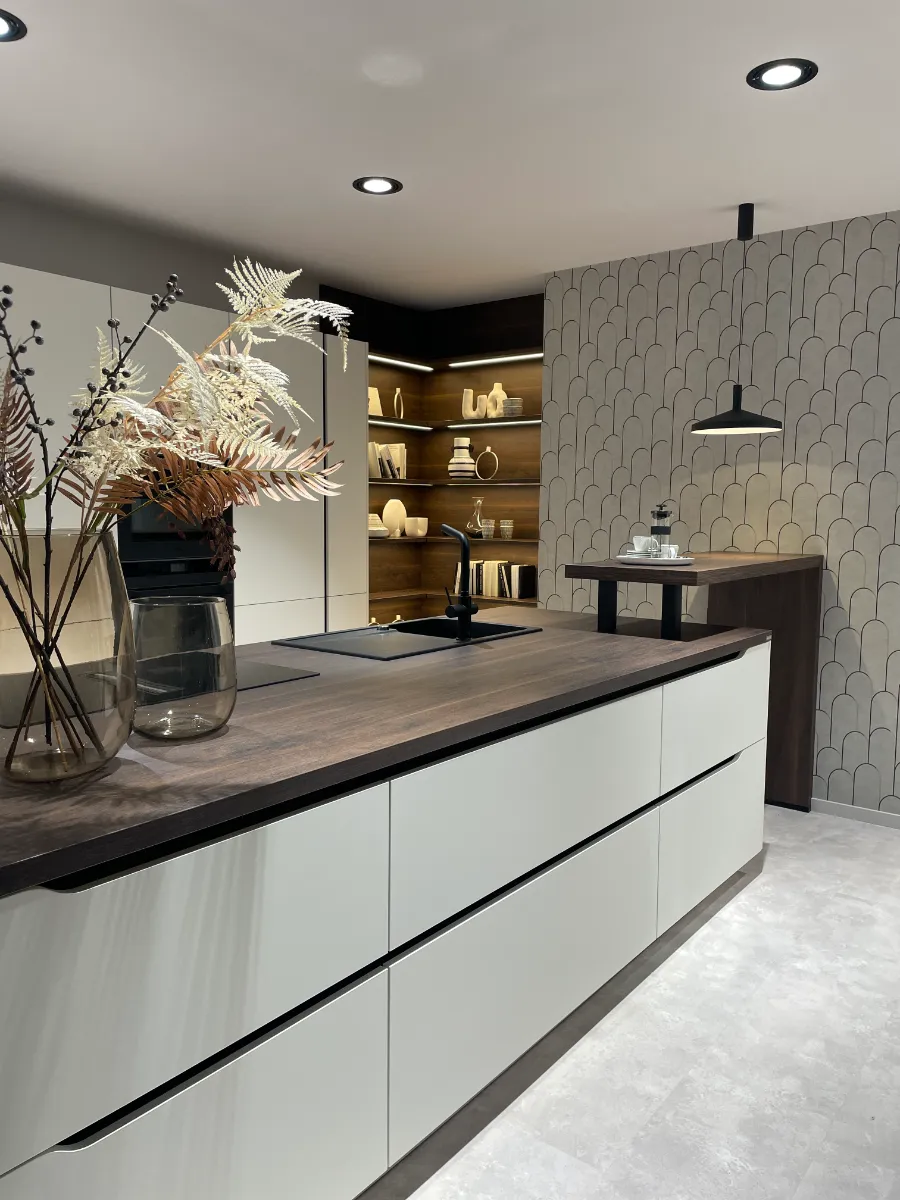 Een moderne keuken met witte aanrechtbladen en een houten eiland.