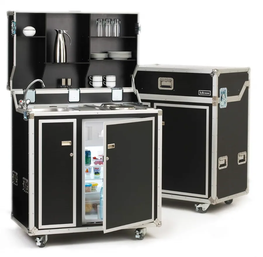 Een keuken op het werk met een zwarte kast, spoelbak en koelkast.