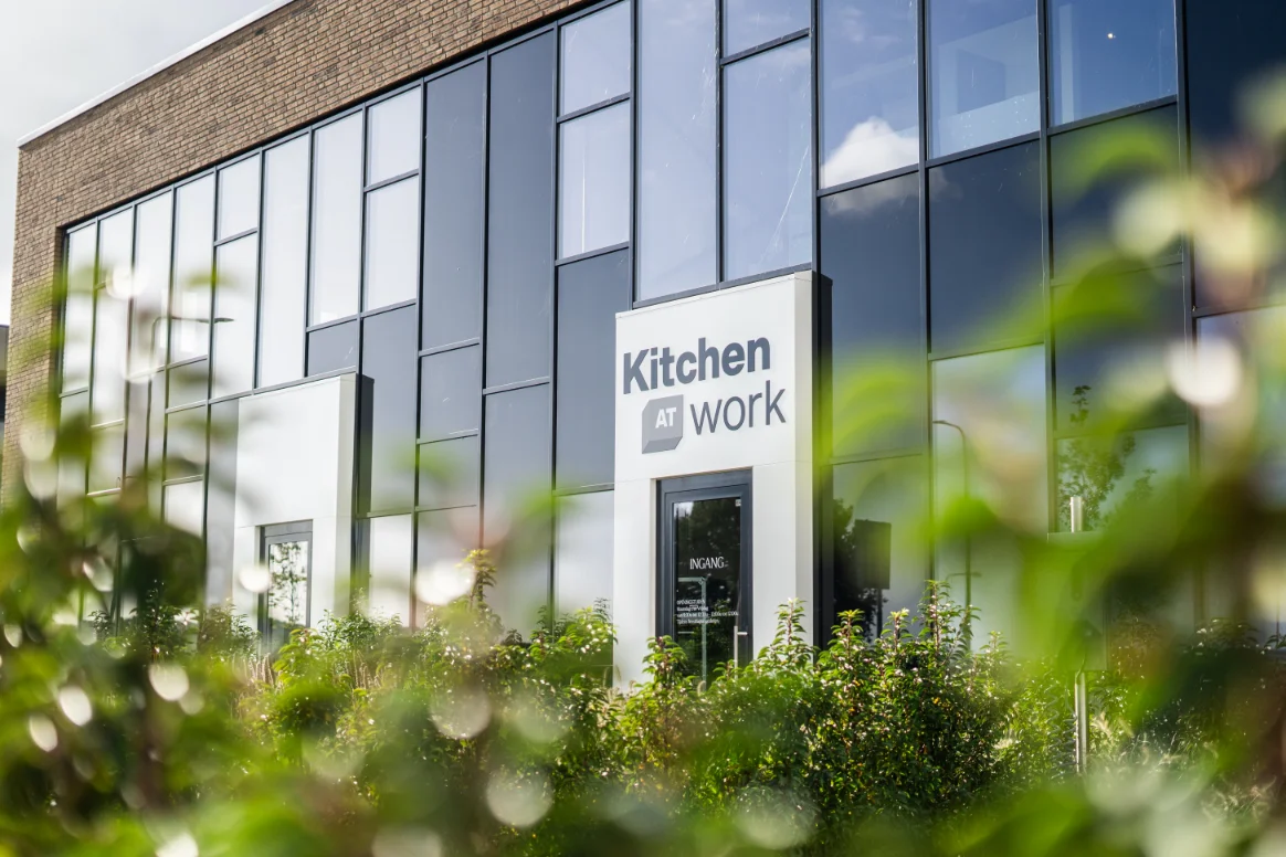 Een kantoorkeukengebouw met struiken ervoor.